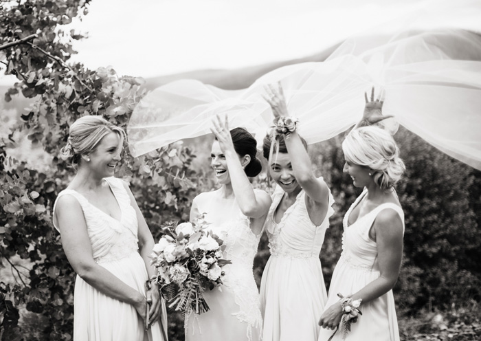 bridal party having some fun with the wedding veil blowing in the wind