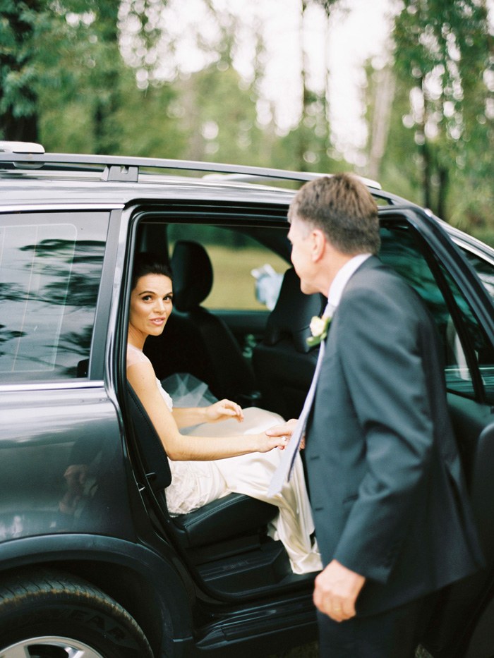 dad helping her daughter the bride get out of the bridal car