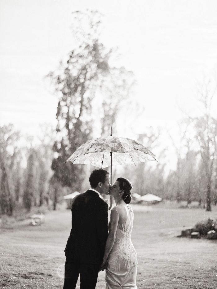 bride and groom in the rain kissing black and white photo