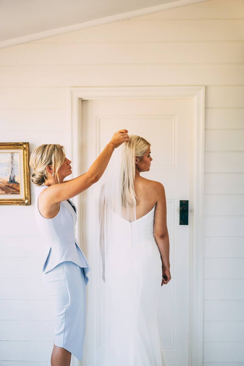 bridesmaid helping bride put the veil on